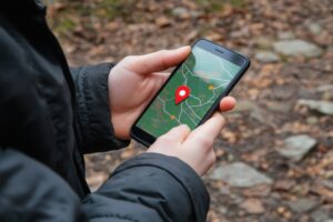 A hand grasps a mobile phone showing a detailed map with a notable location pin as the user navigates an outdoor path. Generative AI